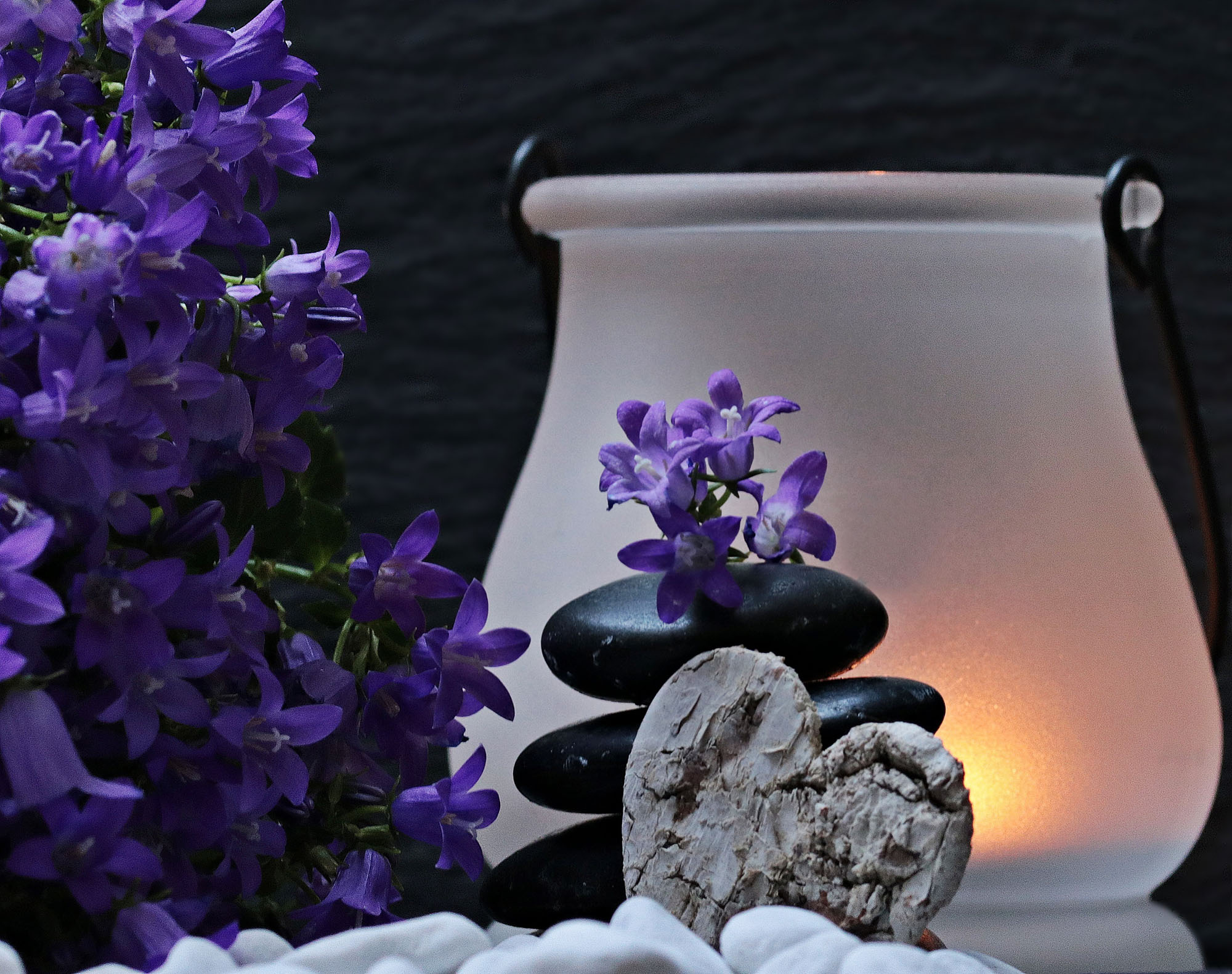 image with a stone heart, blue flowers and a light