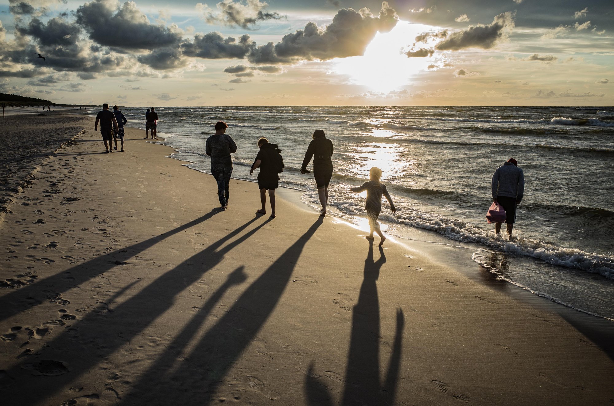 image of beach at sunset and family walking