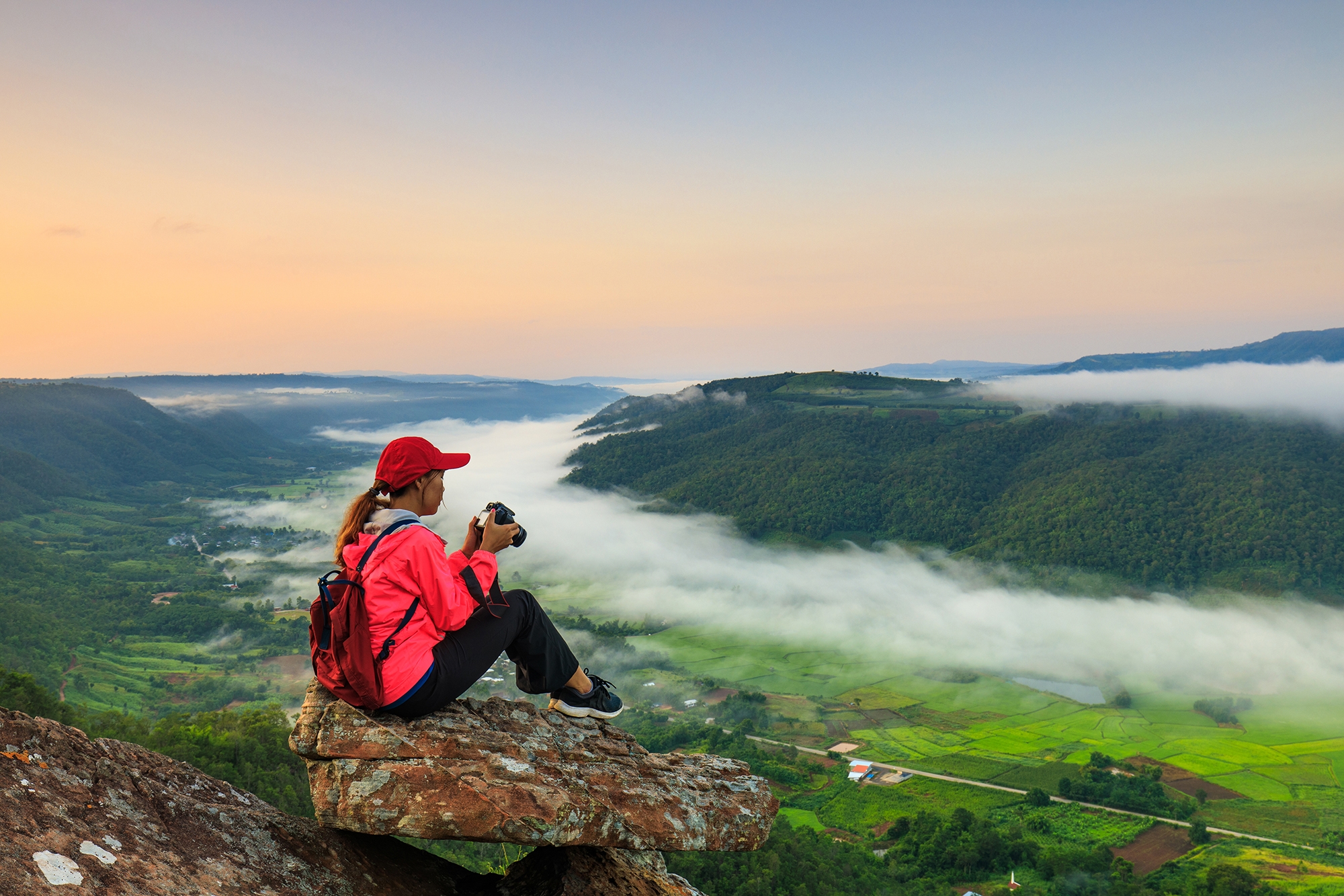 image of a young lady sitting on a mountain top