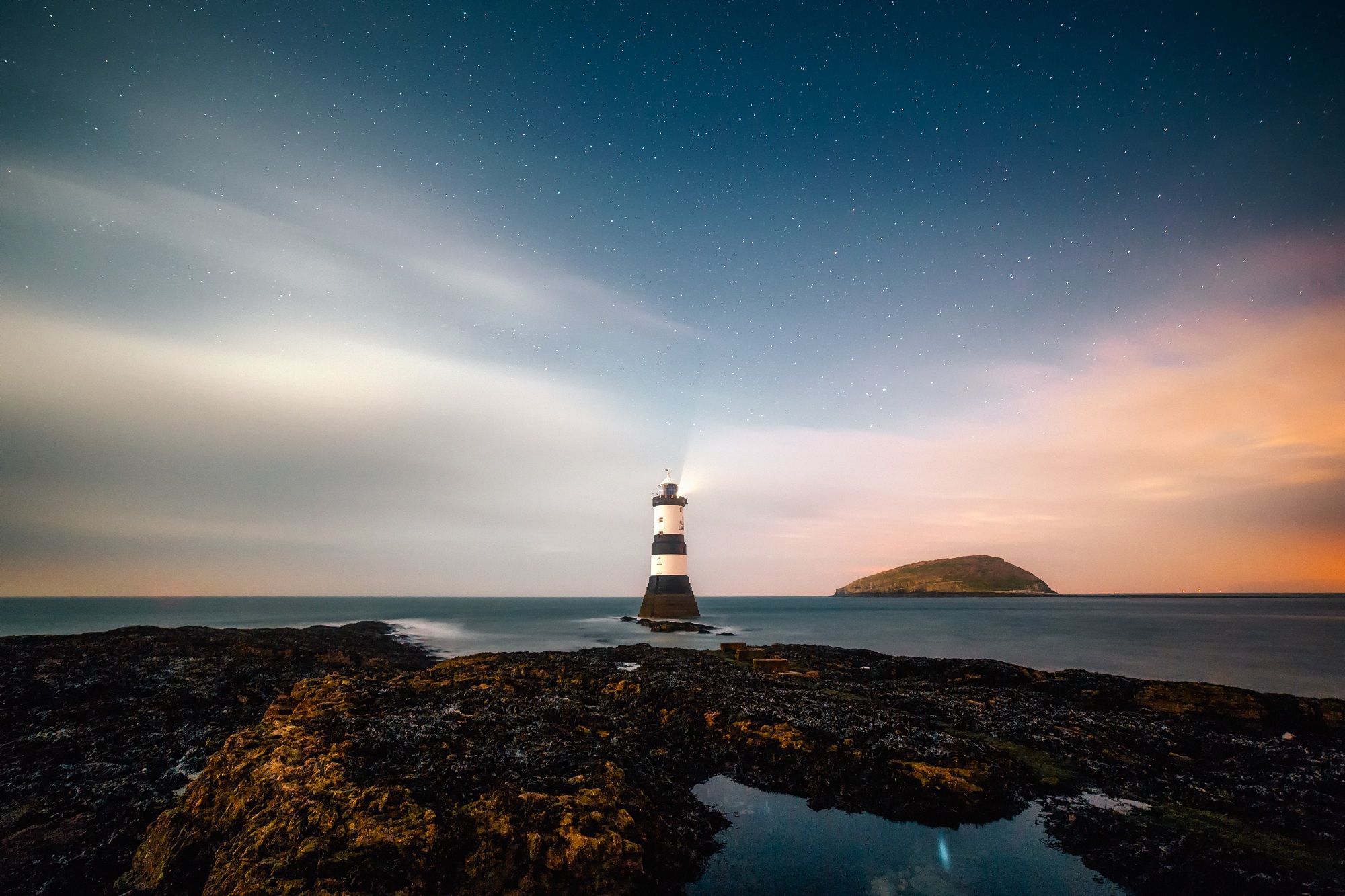 image of lighthouse and a rock on seashore