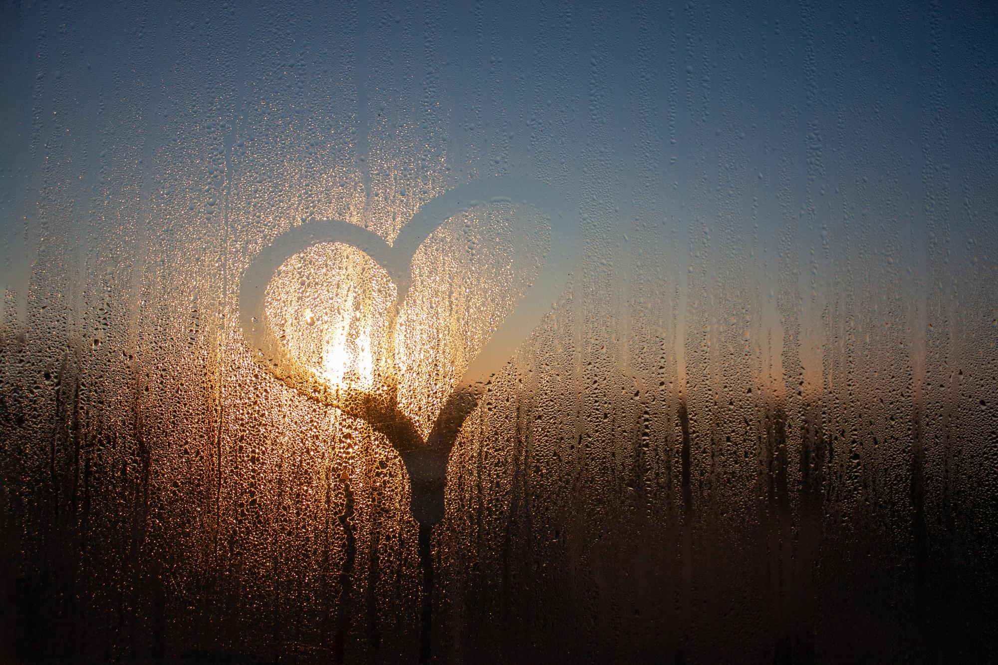 image of a heart shape drawn on a misty window pane
