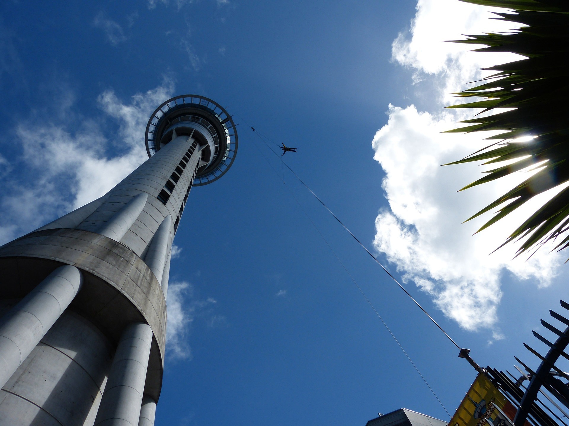 image of a far-away tower against a blue sky and a tiny human figure at the end of a rope
