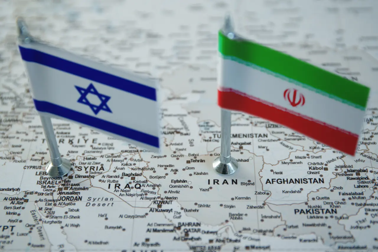 map of Iran and Israel and their flags showing upright stuck into the map