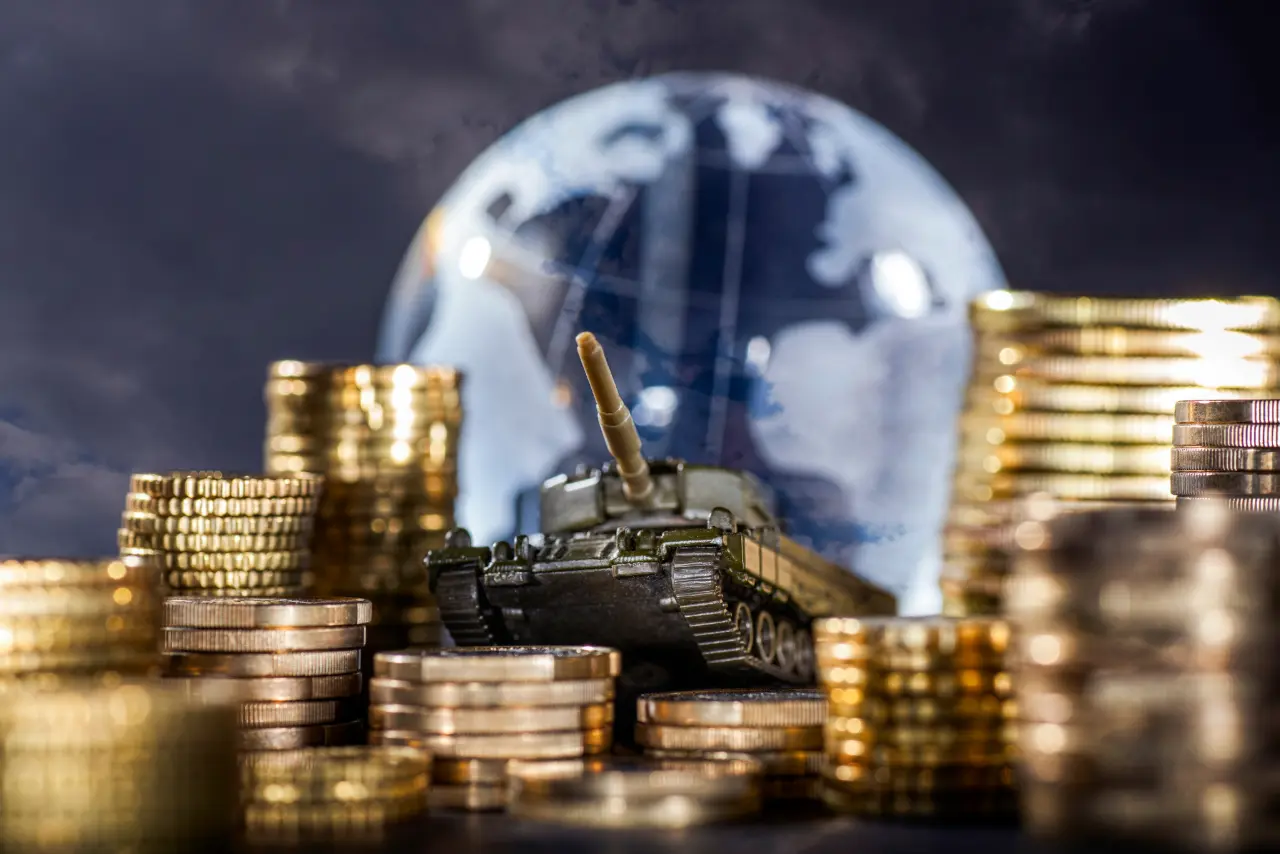 Image of stacks of coins, a small tank in the middle and a globe shape in the background