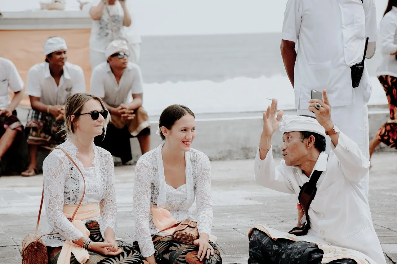 Image of two women and a man from different cultures, sitting in a public place and friendly talking and listening to each other