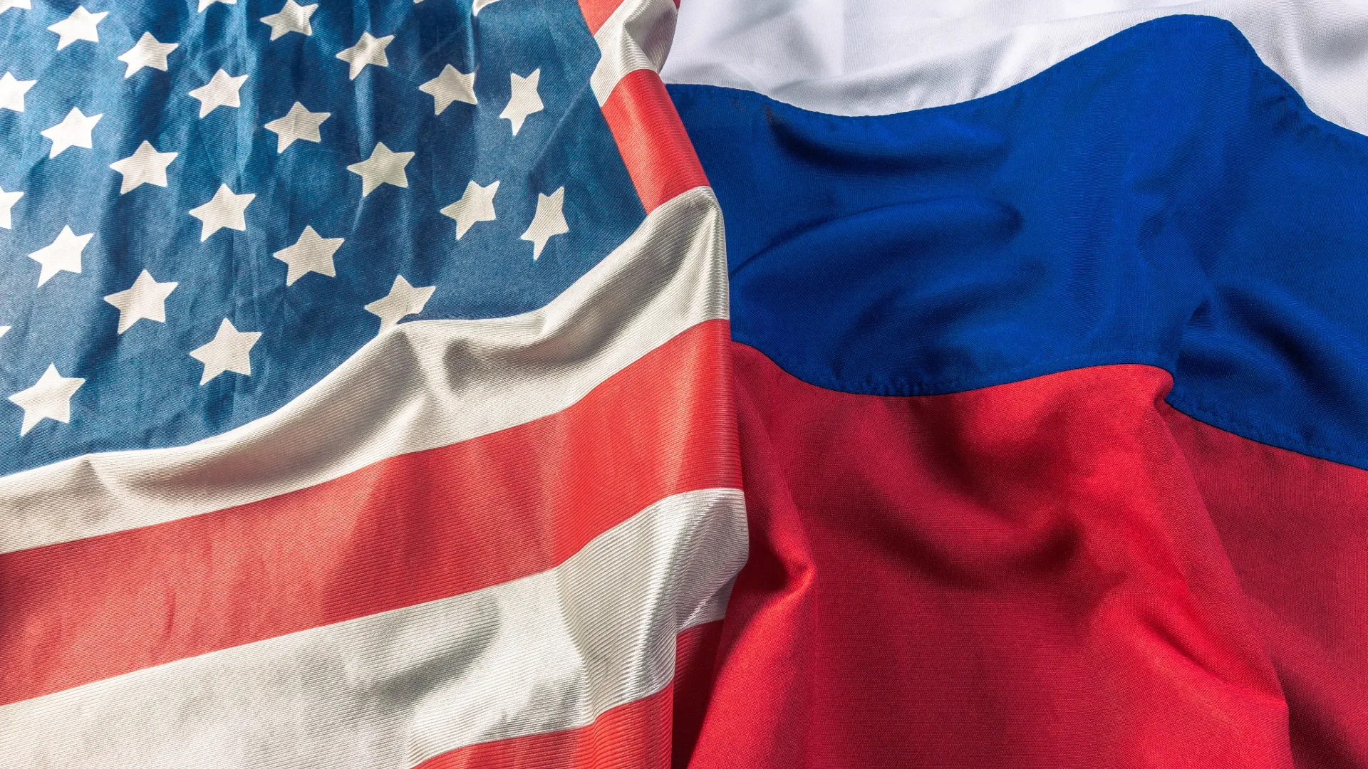 The flags of the USA and Russia closely together, in folds, as if laid out on a table.