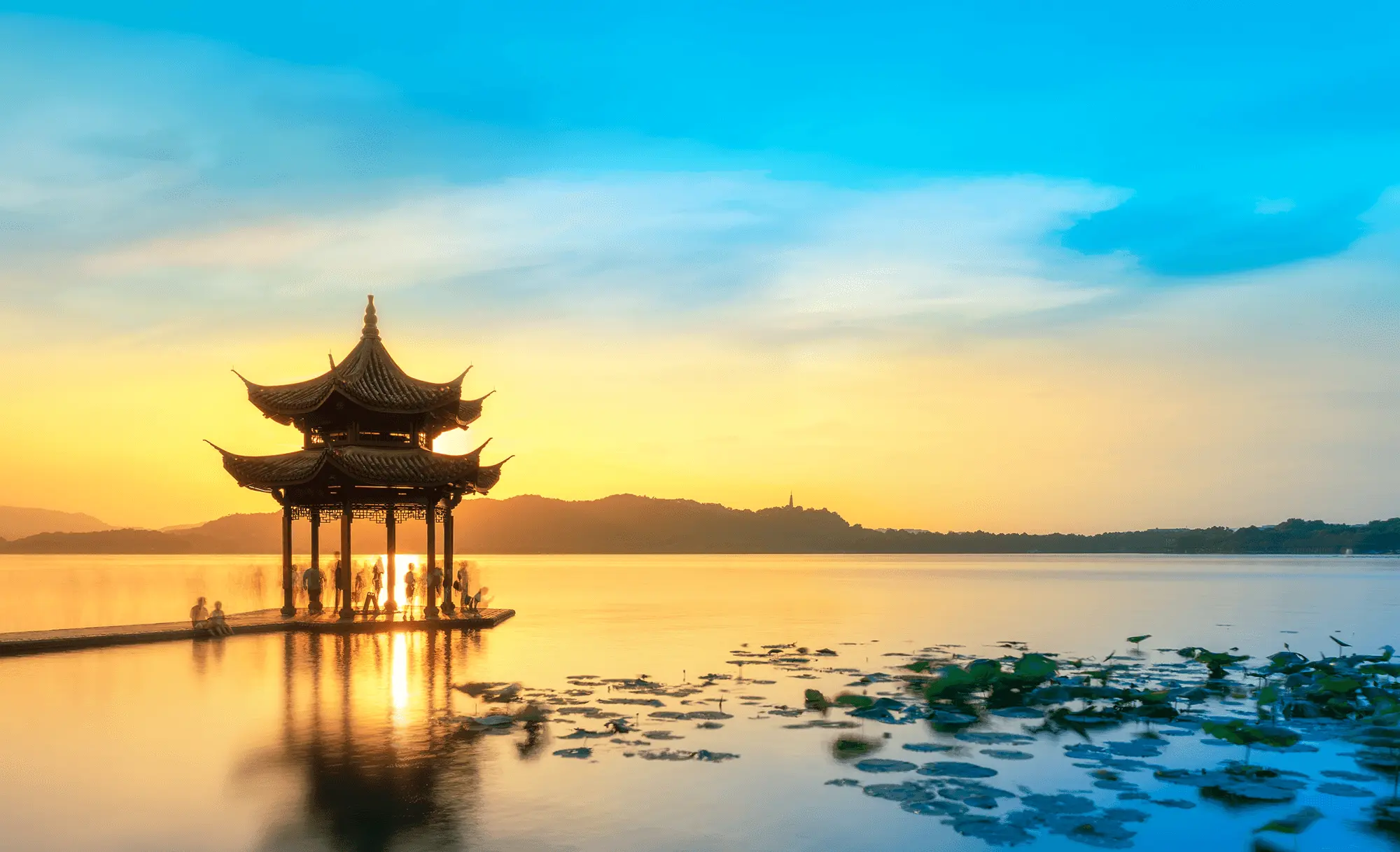 Sunset at a lake, with a pavilion shape against the sunlight, providing a sense of calm.