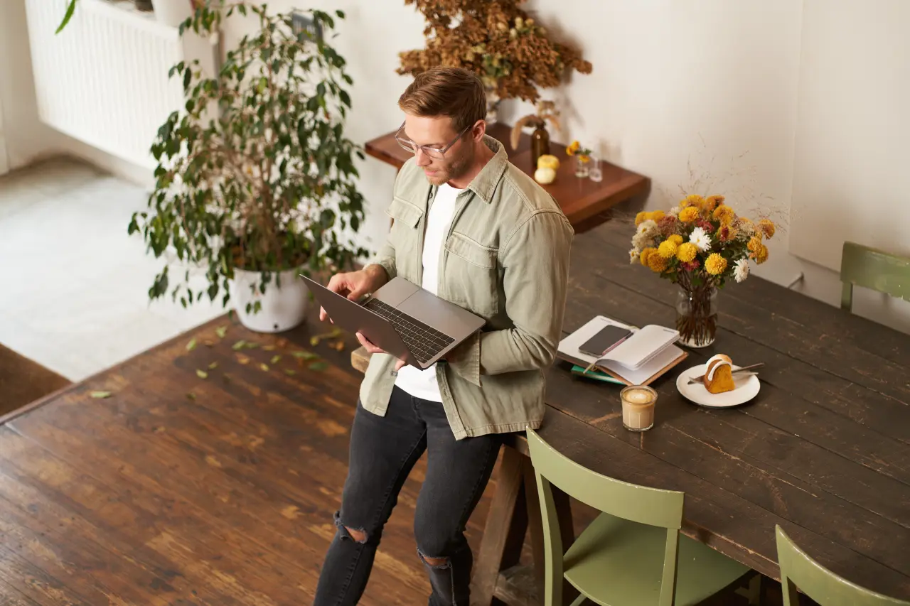 young man in home office looking thoughtfully at his laptop screen