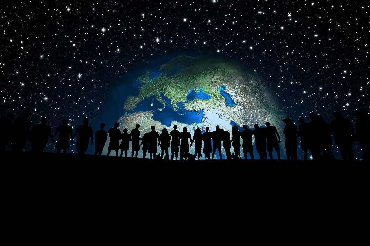 image of a globe in the night sky, with a large group of people on ground in shadow standing in front of it