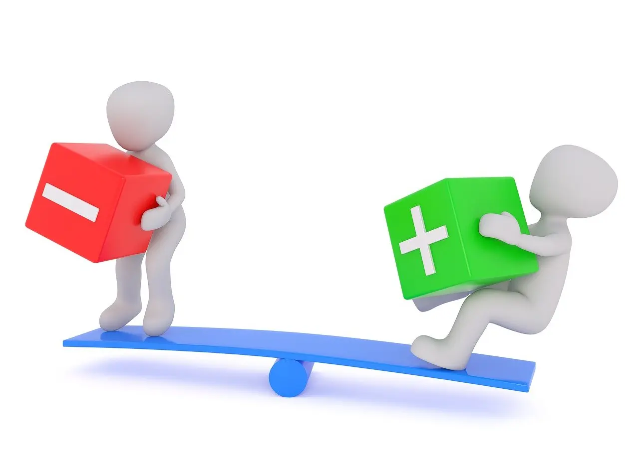 Zwei kleine Spielfiguren auf einer Wippe, eine hält einen Würfel mit einem Pluszeichen, eine einen Würfel mit einem Minuszeichen in den Händen. Sie scheinen Mühe z haben, die Wippe im Gleichgewicht zu halten.