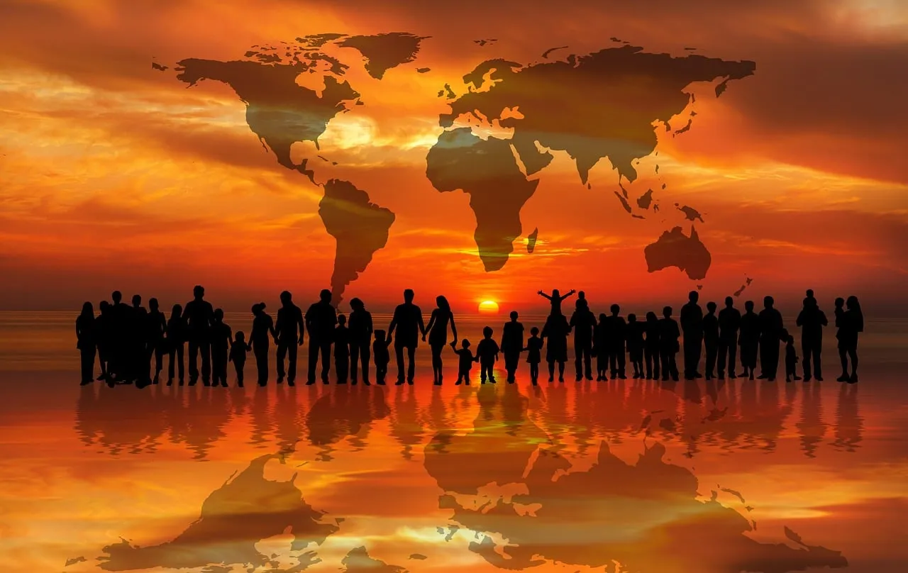 Die Weltkarte vor einem Sonnenuntergang mit Silhouetten von Menschen, Männer, Frauen, Kinder, davor.